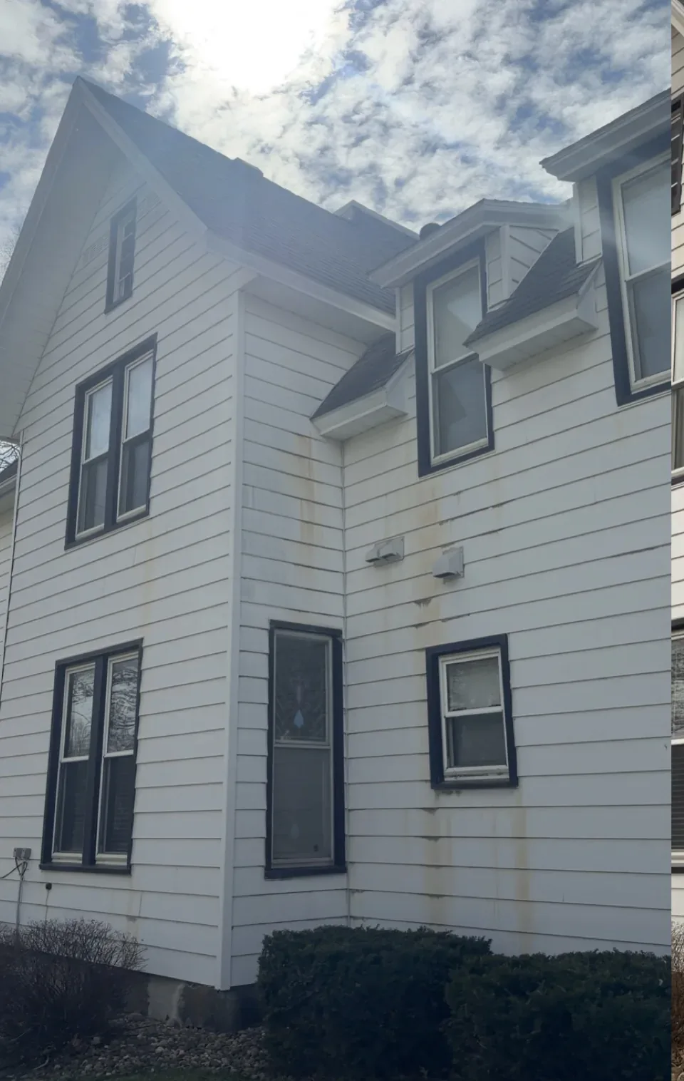 Two-story white siding home, green algae on the north wall, before