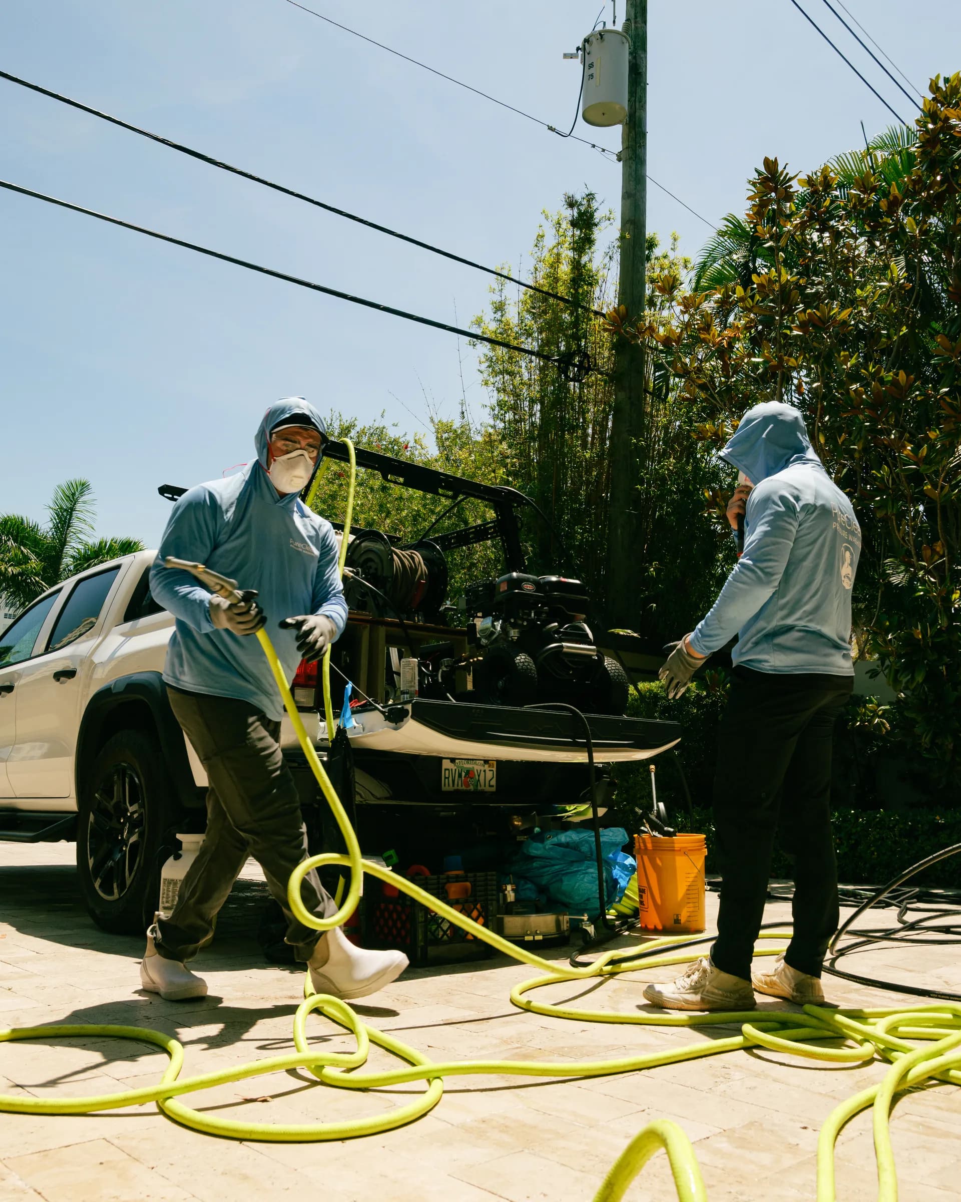 Crew pulling hose off the rig on a paver driveway