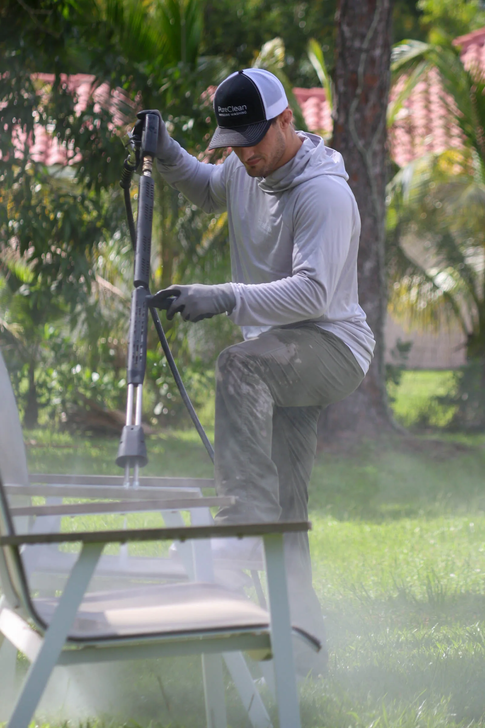 Michael washing outdoor furniture in a planted backyard with a barrel-tile roof behind