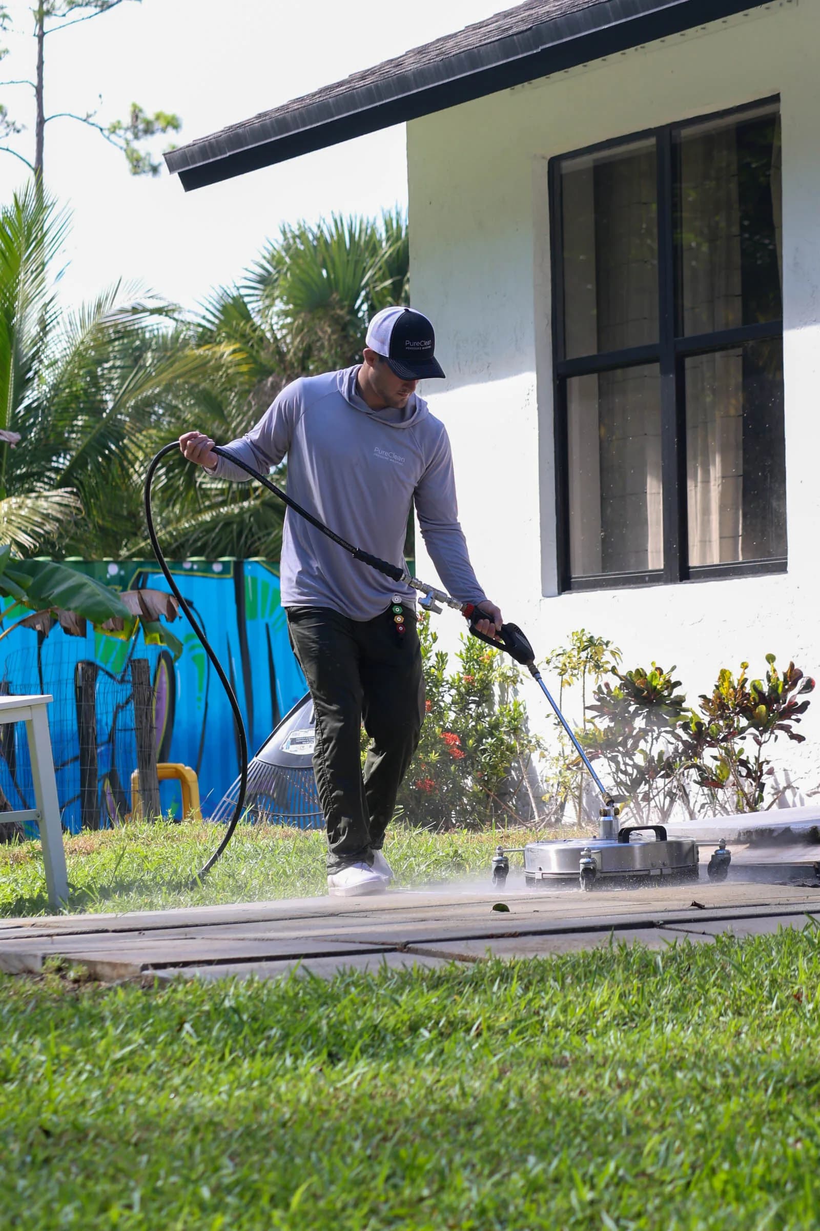 Michael running a surface cleaner beside a stucco house