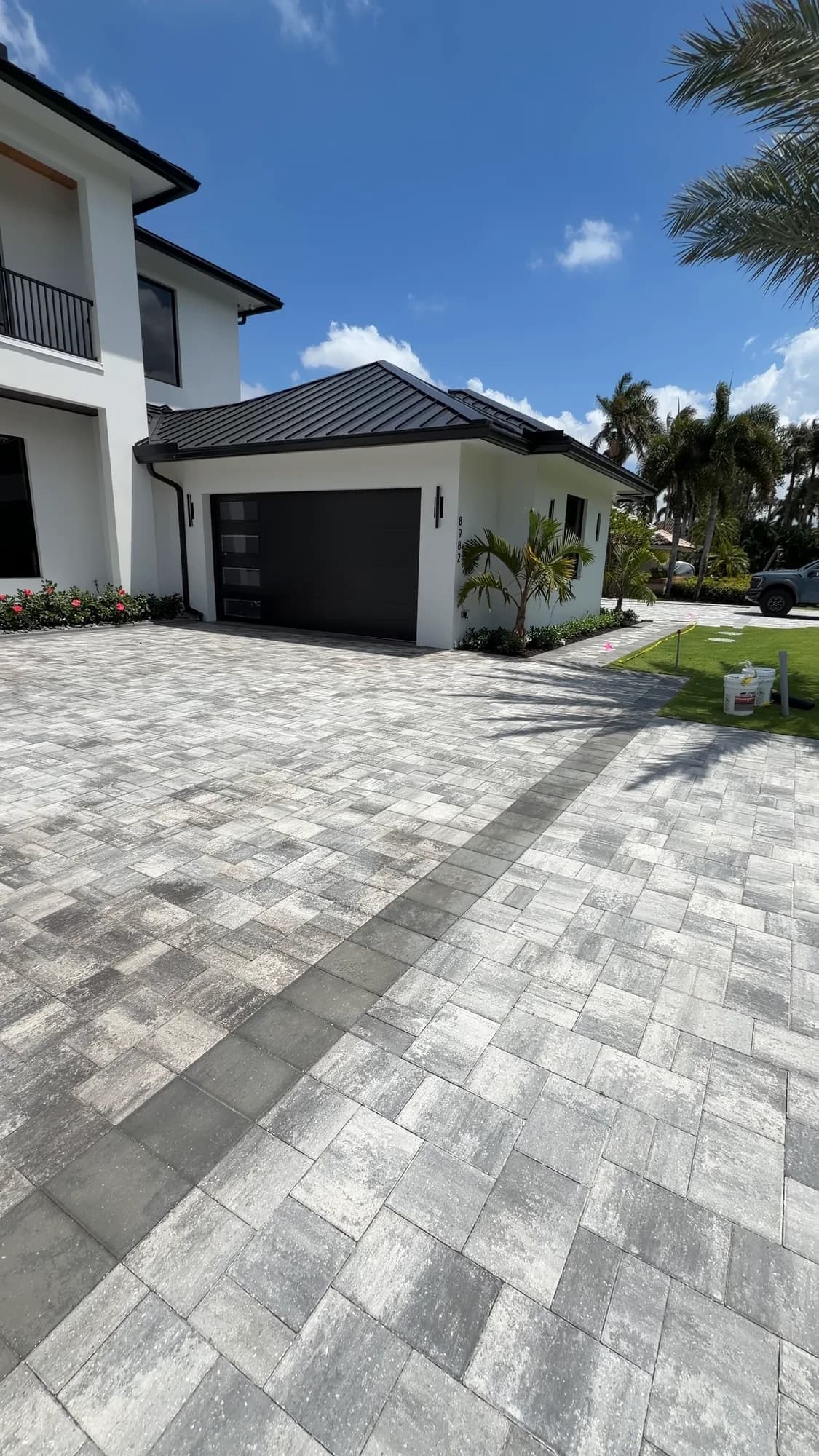 A modern white home and paver driveway photographed from the street