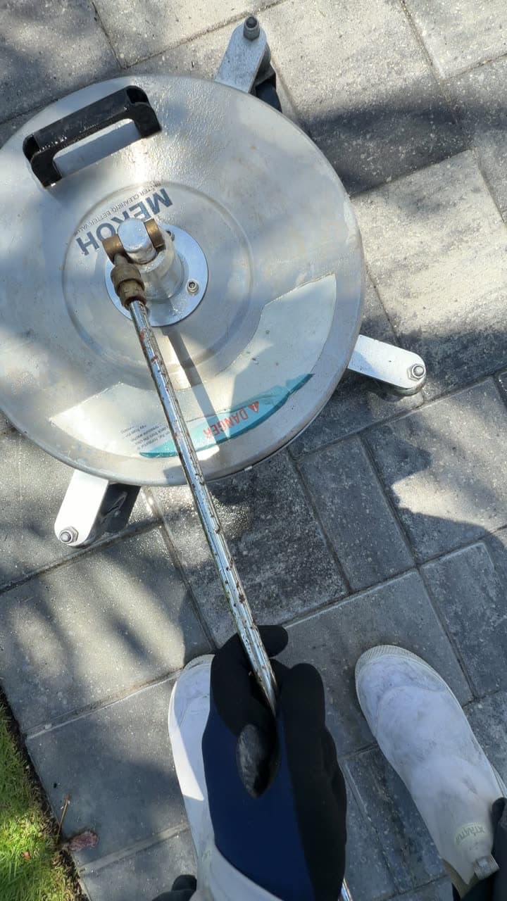 Surface cleaner on a paver driveway under palm shadows